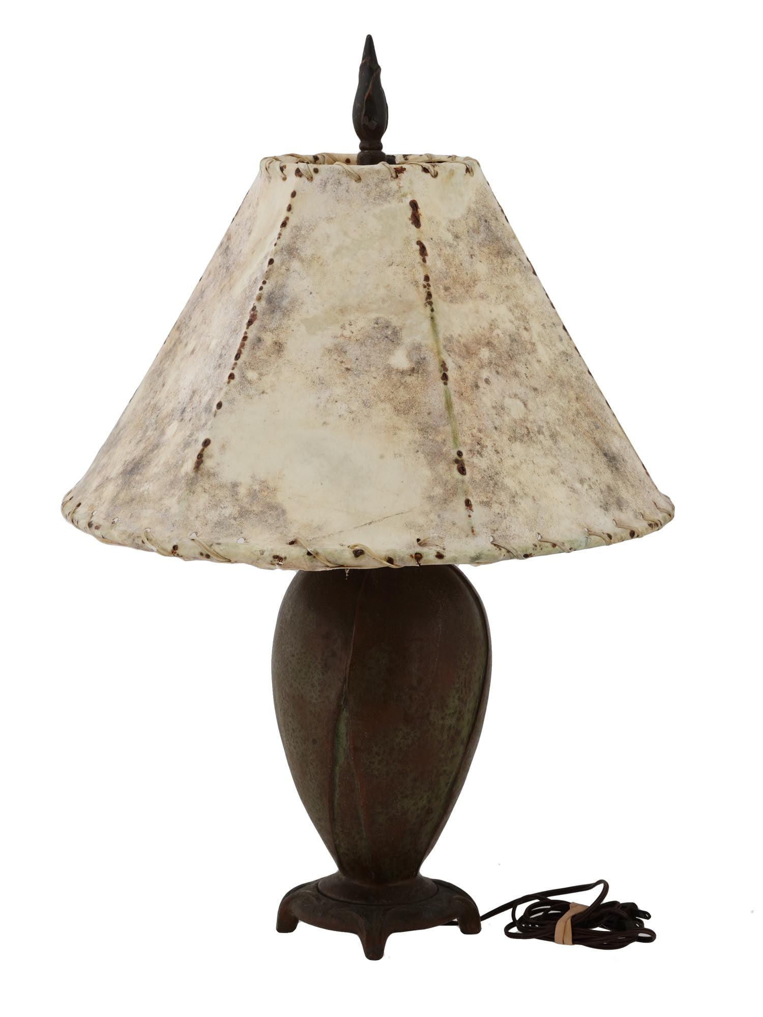 VINTAGE PATINATED BRONZE DESK LAMP W LEATHER SHADE: A vintage patinated bronze desk lamp. A body is made in a bud design. Completed with a burnt leather shade. Mounted on a base with four legs. Unmarked. Vintage and Modern Bronze Table Lamps, Desk Ware