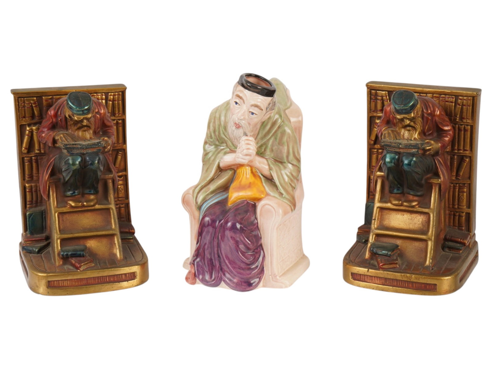 VINTAGE SHYLOCK TOBY JUG AND JUDAICA BOOK ENDS: A hand-painted toby jug by Melba Ware, Stoke-on-Trent. Shylock from Shakespeares play The Merchant of Venice. The lot also includes a pair of vintage bronze bookends representing a Jewish man in a lib