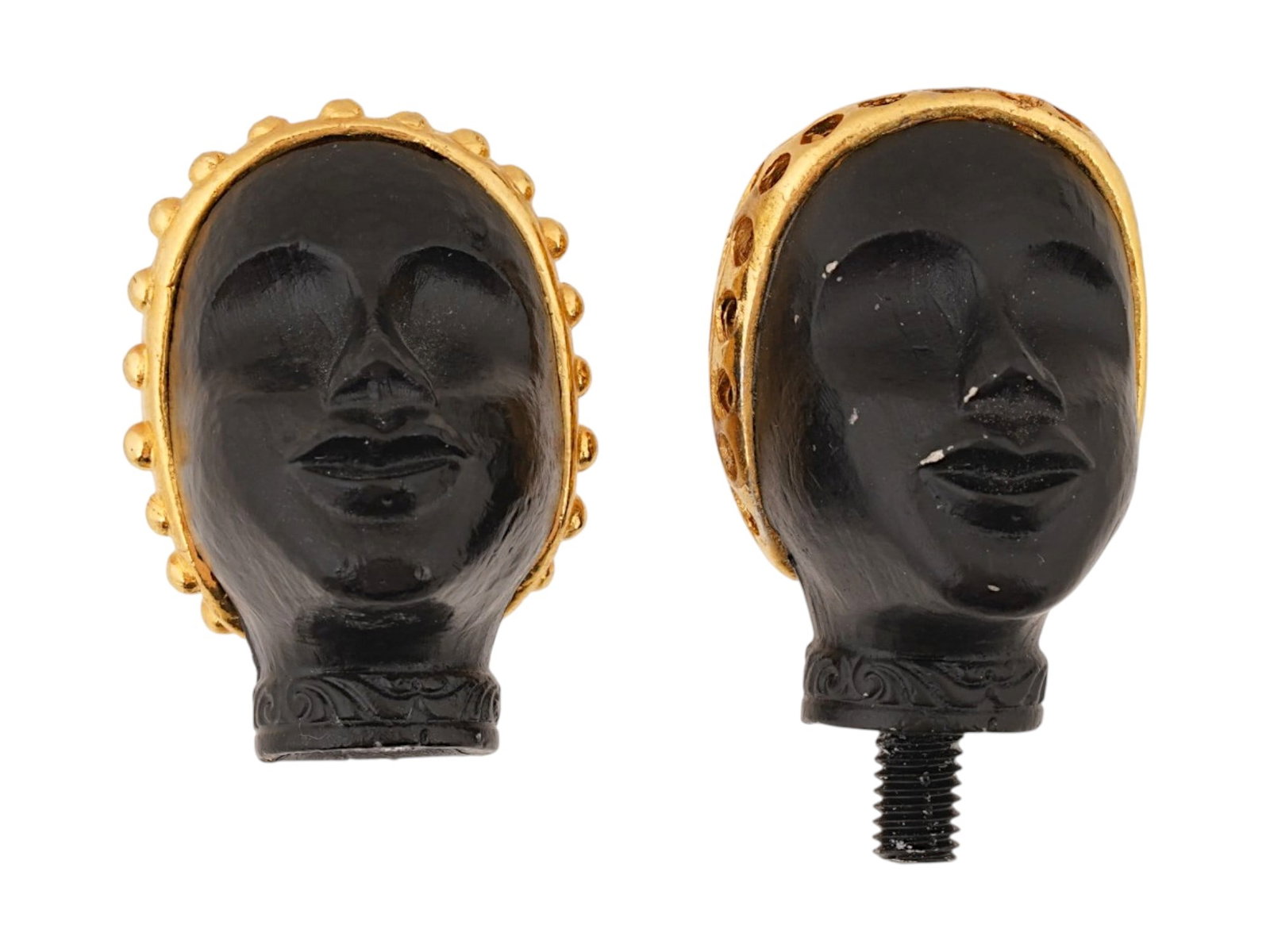 PAIR OF FIGURAL HEAD FINIALS ATTR TO FLORENZA: A pair of figural finials or handles, attributed to Florenza. The wares depict two stylized female heads crafted from a matte black molded material. Each head is adorned with a decorative gold tone me