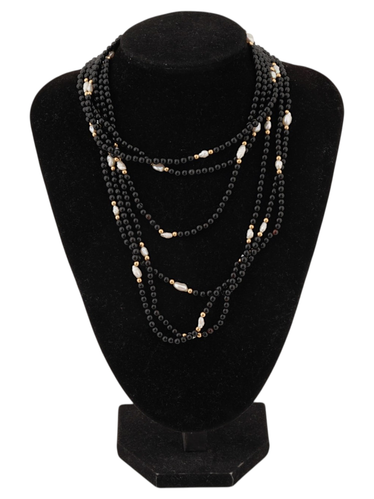 VINTAGE MULTI STRAND ONYX AND GOLD BEAD NECKLACE: A vintage multi-strand necklace composed of polished black onyx beads accented with luminous freshwater rice pearls. The design is enhanced by gold-toned spacer beads and a decorative clasp. Vintage N