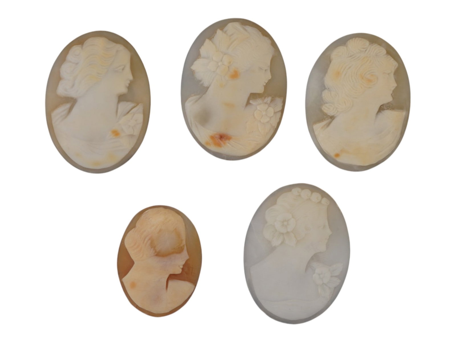 COLLECTION OF FEMALE PORTRAIT CARVED SHELL CAMEOS: A collection of hand carved shell cameos. A total of 5 items. Each piece depicts a female profile portrait rendered in high relief in the Victorian manner. Each cameo is fashioned in a distinctive