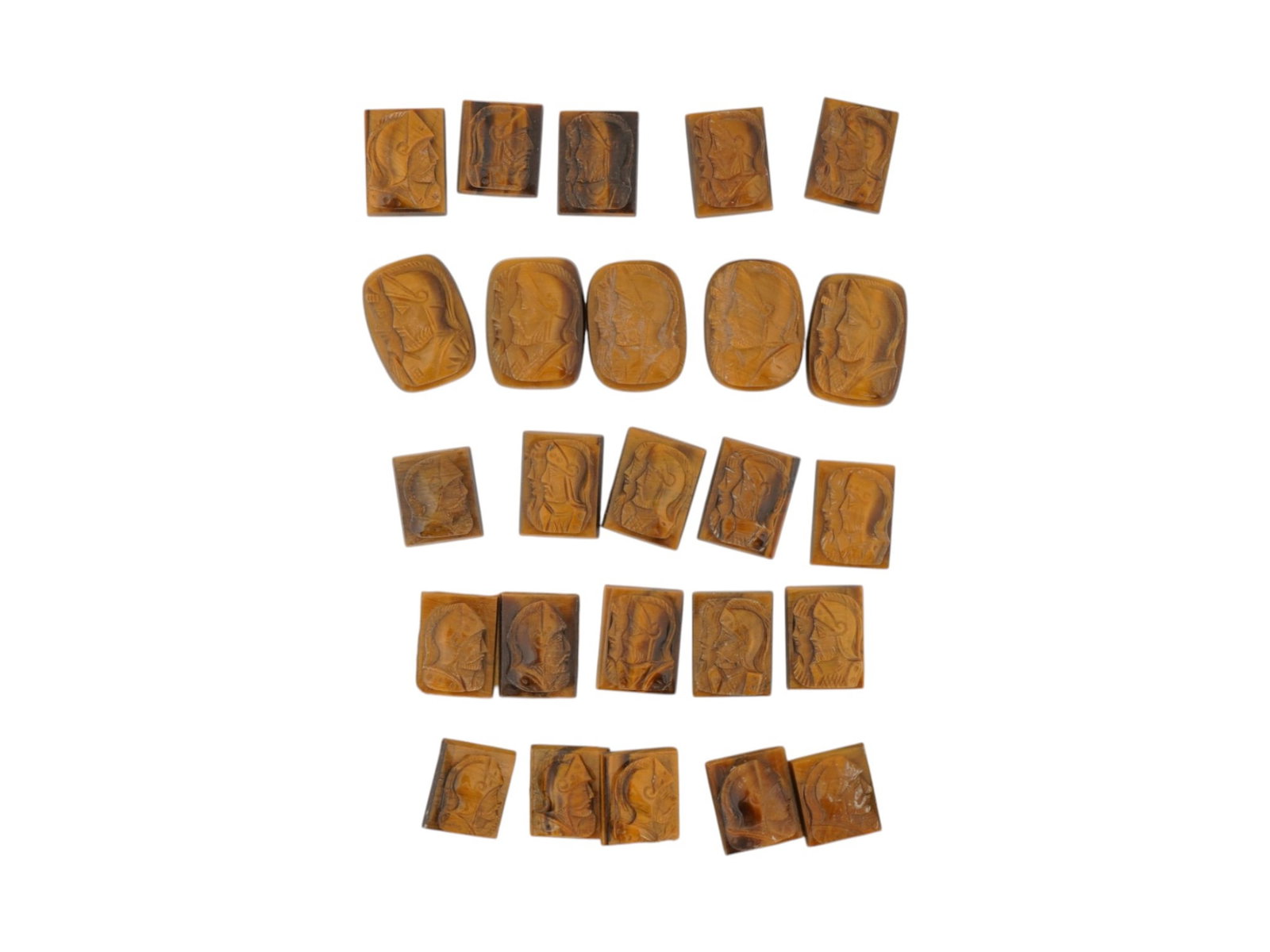 COLLECTION OF 25 HAND CARVED TIGERS EYE STONE CAMEOS: A collection of 25 hand-carved tigers eye stone cameos featuring profile portraits in raised relief. The carvings depict classical and historical figures, including warriors and armored busts, rendere