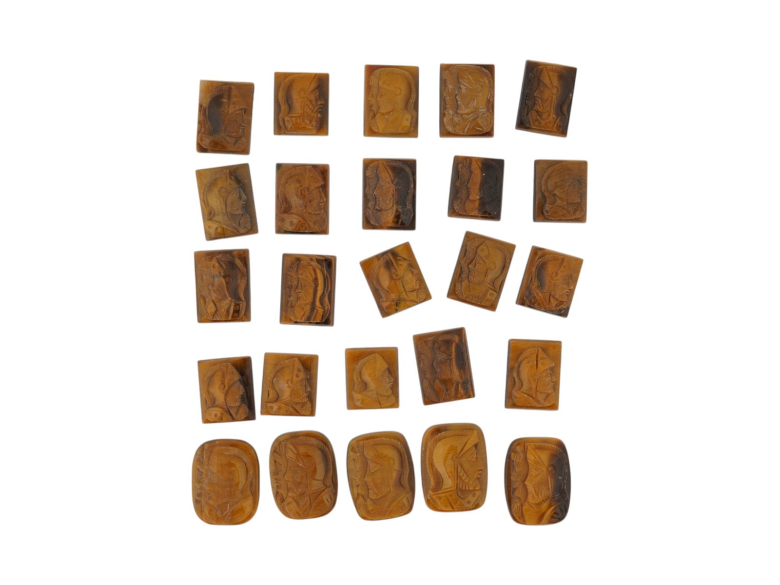 COLLECTION OF 25 HAND CARVED TIGERS EYE STONE CAMEOS: A collection of 25 hand-carved tigers eye stone cameos featuring profile portraits in raised relief. The carvings depict classical and historical figures, including warriors and armored busts,