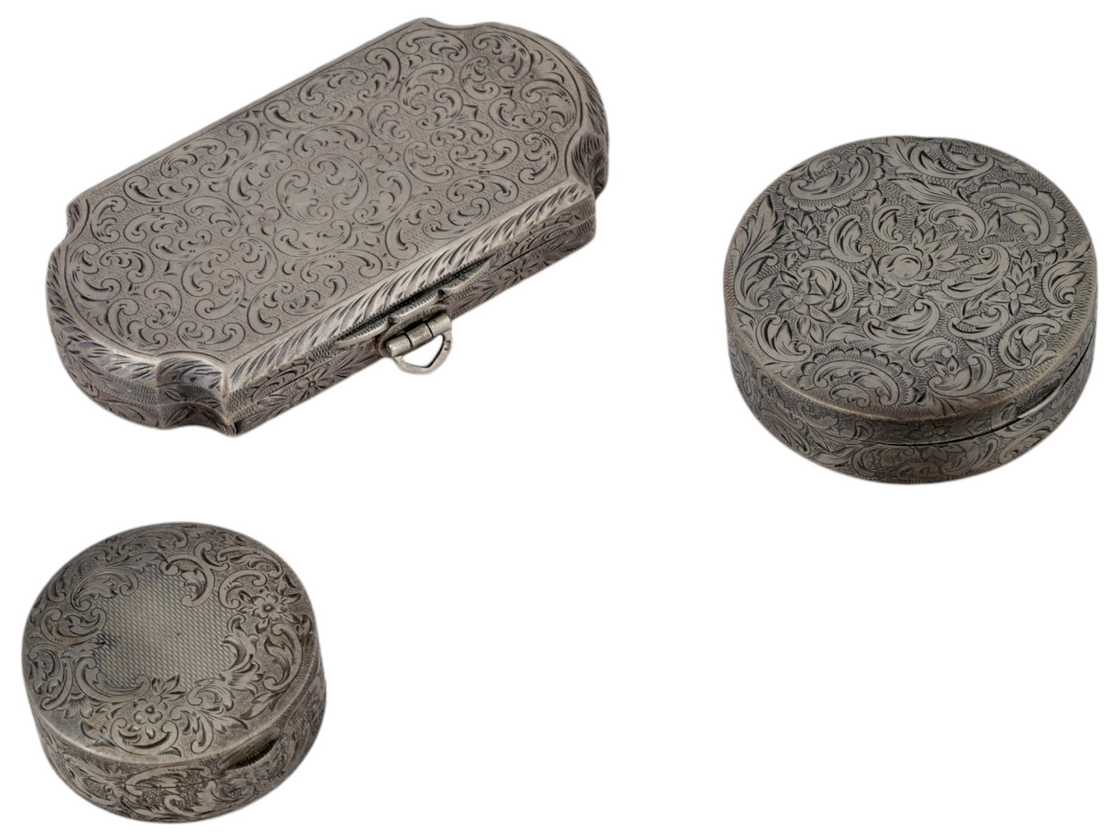 ANTIQUE EUROPEAN STERLING SILVER POWDER COMPACTS: A lot of three antique European sterling silver powder compacts. Circa the late 19th to early 20th century. Two powder compacts are round in shape, with a hinged lid. Inside the smaller one there is a