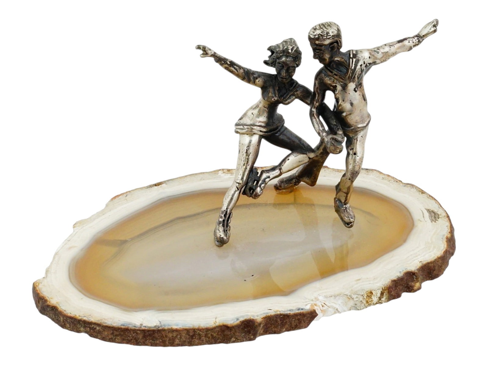 SILVER PLATED DANCING COUPLE SCULPTURE ON STONE BASE: A decorative sculpture featuring two Silver plated figures representing a couple in a mid dance or skating pose. Mounted upon a polished slice of stone base. The figures exhibit detailed casting, capt