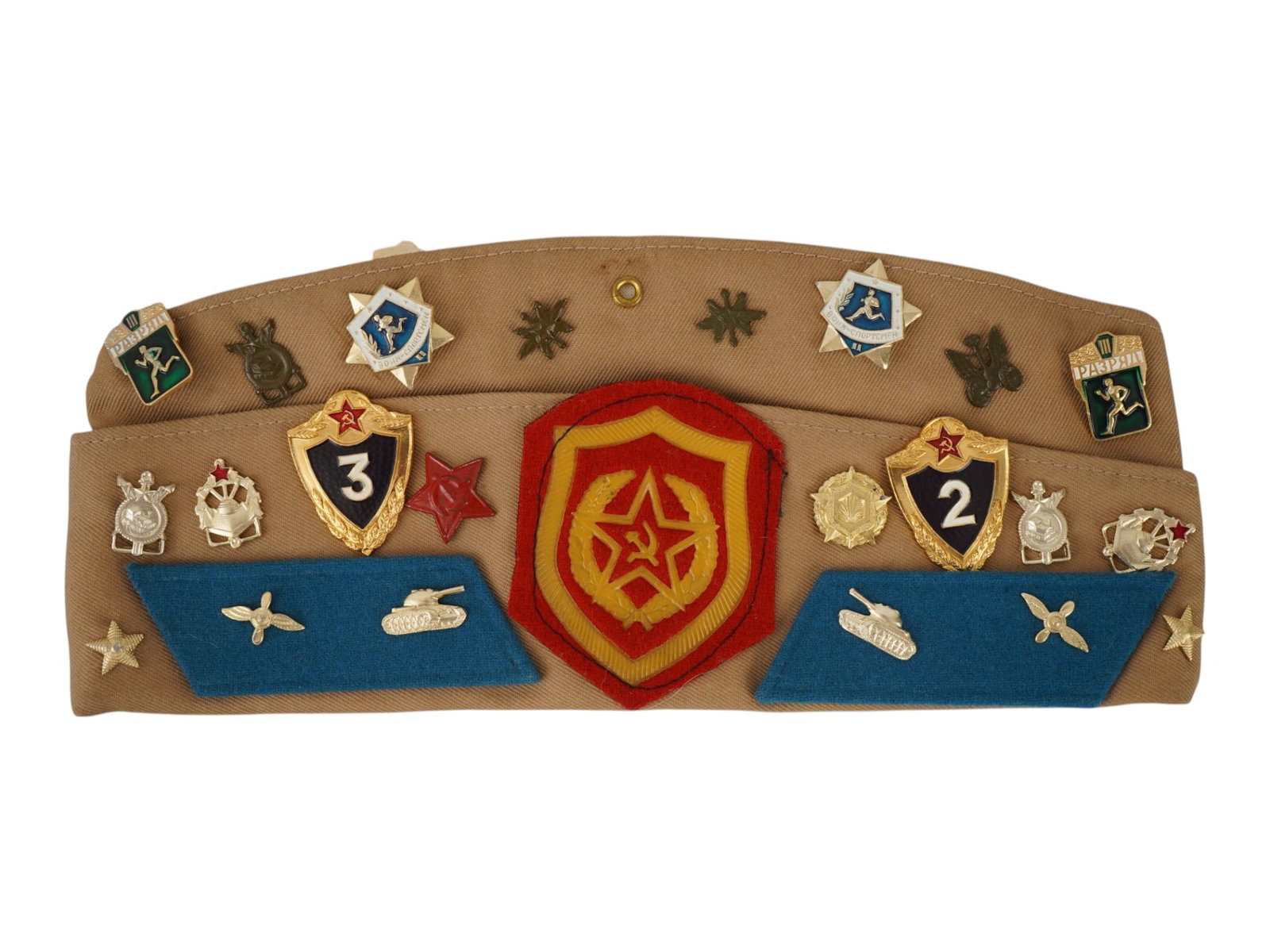 SOVIET PILOTKA CAP MOTORIZED RIFLE TROOPS W BADGES: A vintage Soviet Pilotka cap of the USSR Motorized Rifle Troops, model 1969, with numerous badges and patches. The cap bears insignia, including tank collar tabs, sports badges, and sports rank insign