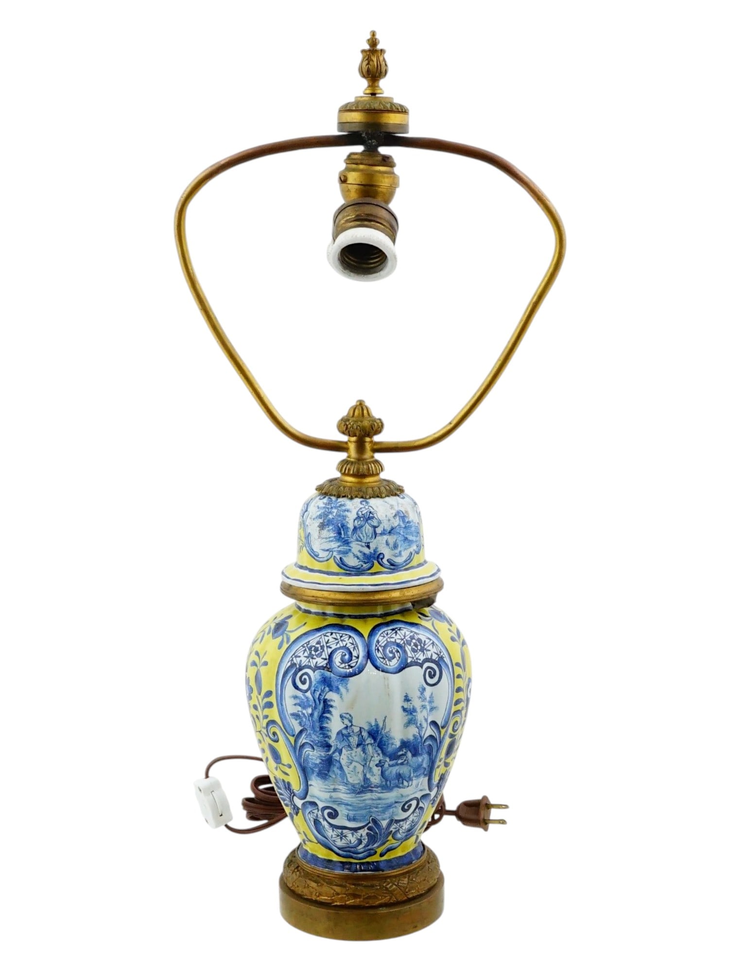 ANTIQUE FRENCH DELFT STYLE PORCELAIN BRONZE VASE LAMP: An early 20th-cenutry French porcelain lidded vase converted into a table lamp with electrical fittings. Classic baluster shape. Delft-style hand-painted cobalt blue pastoral scenes against the yellow