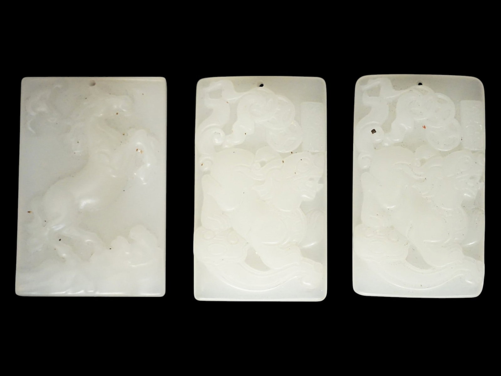 LOT OF CHINESE HETIAN JADE PENDANT PLAQUES: A lot of three Chinese hand-carved Hetian jade pendants. Rectangular format. Bas-relief horse and foo dog motifs. Collectible Oriental Asian Gemstone Jewelry. THIS LOT IS ELIGIBLE FOR A 30-DAY UNCONDI