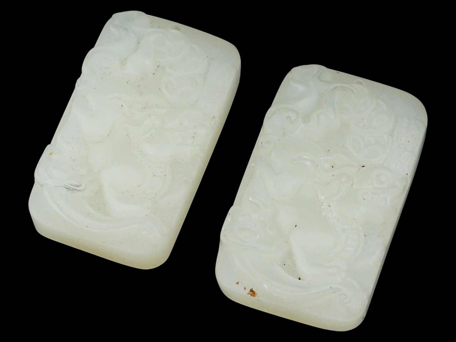 PAIR OF CHINESE RECTANGULAR WHITE JADE PENDANTS: A pair of identical Chinese rectangular pendants, hand-carved from white jade. Both pieces depict a relief mythical creature. A hanging hole is at the top. Collectible Oriental Asian Gemstone Jewelry.