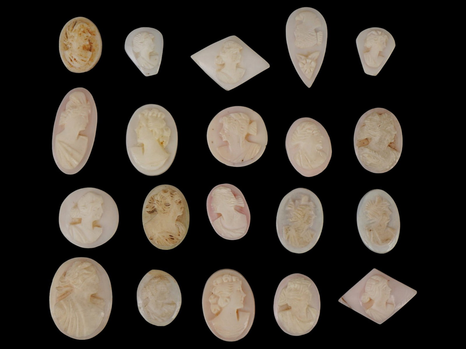 COLLECTION OF FEMALE PORTRAIT CARVED CORAL CAMEOS: A collection of hand carved pink coral cameos. A total of 20 items. Each piece depicts a female profile portrait rendered in high relief. Oval, square, and drop shape. Collectible Jewelry And Glyptic 