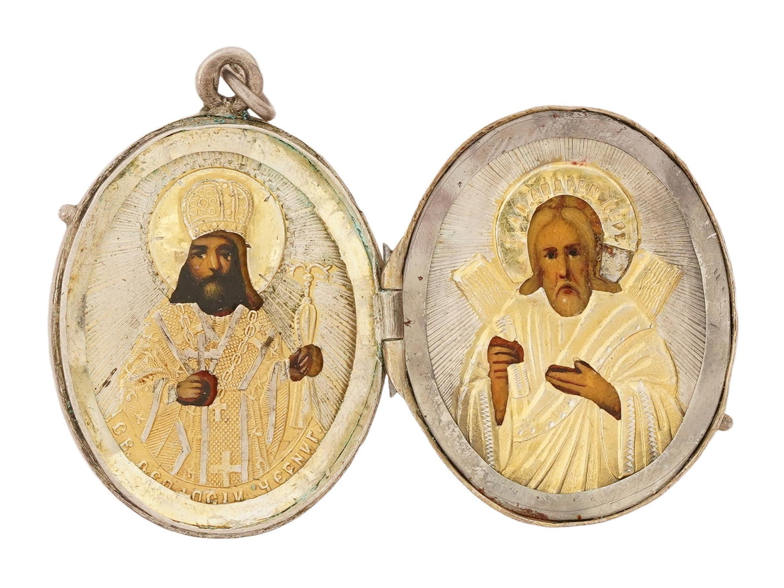 ANTIQUE RUSSIAN ORTHODOX SILVER ENAMEL ICON PENDANT: An antique Russian Orthodox hand-painted oval icon pendant depicting Saint Andrew and Saint Feodosiy, overlaid with a repousse and chased silver oklad. The exterior is embellished with an engraved cro