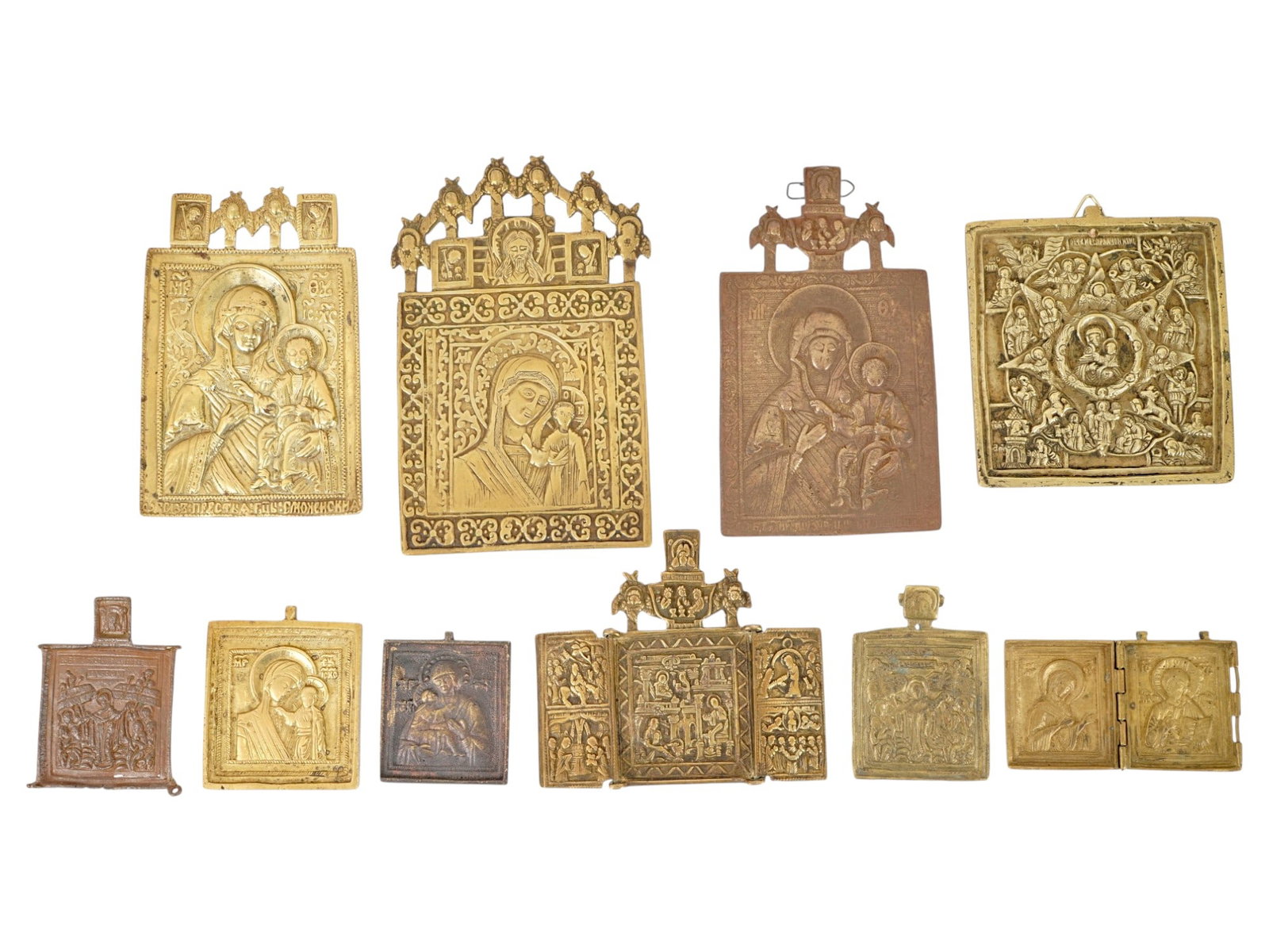 COLLECTION OF RUSSIAN ORTHODOX CAST METAL ICONS: A collection of Russian Orthodox cast metal icons, including single plaques, a folding triptych, and a small diptych. Executed in brass or bronze alloy, the pieces feature traditional hagiographic sub