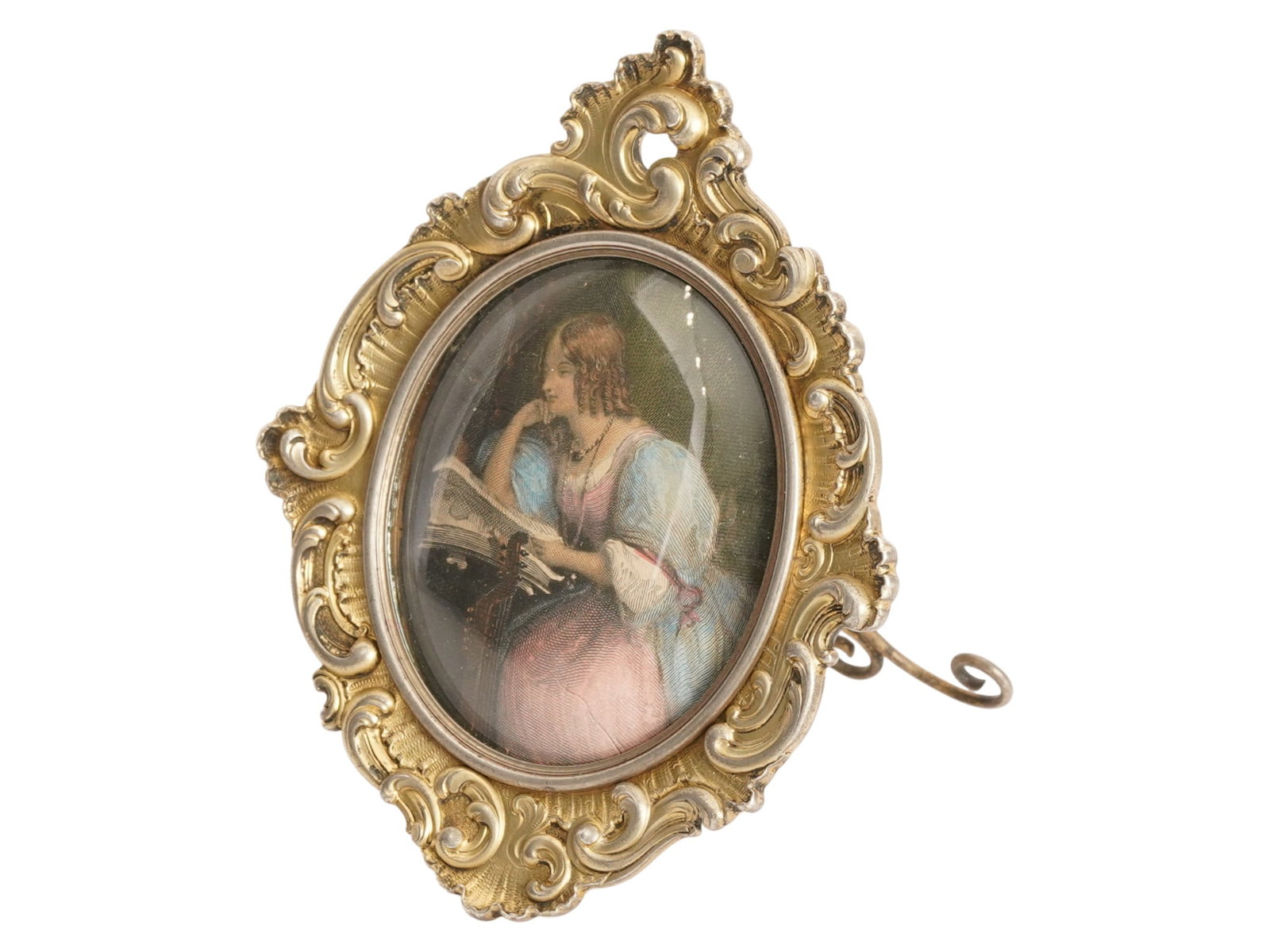 FABERGE RUSSIAN GILT SILVER STANDING PICTURE FRAME: An Imperial Russian gilt silver standing picture frame. Oval piece with embossed scroll motif and figurative rim. The picture hole features a colored engraving of a woman with a book. Hallmark of 88