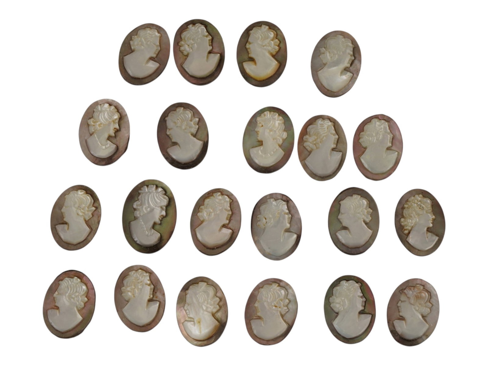 LOT OF CARVED FEMALE PORTRAIT SHELL CAMEO MEDALLIONS: A collection of twenty one hand carved shell cameo medallions. The pieces depict a female profile portrait rendered in high relief in the Victorian and Roman manners. Each cameo is fashioned in a dist