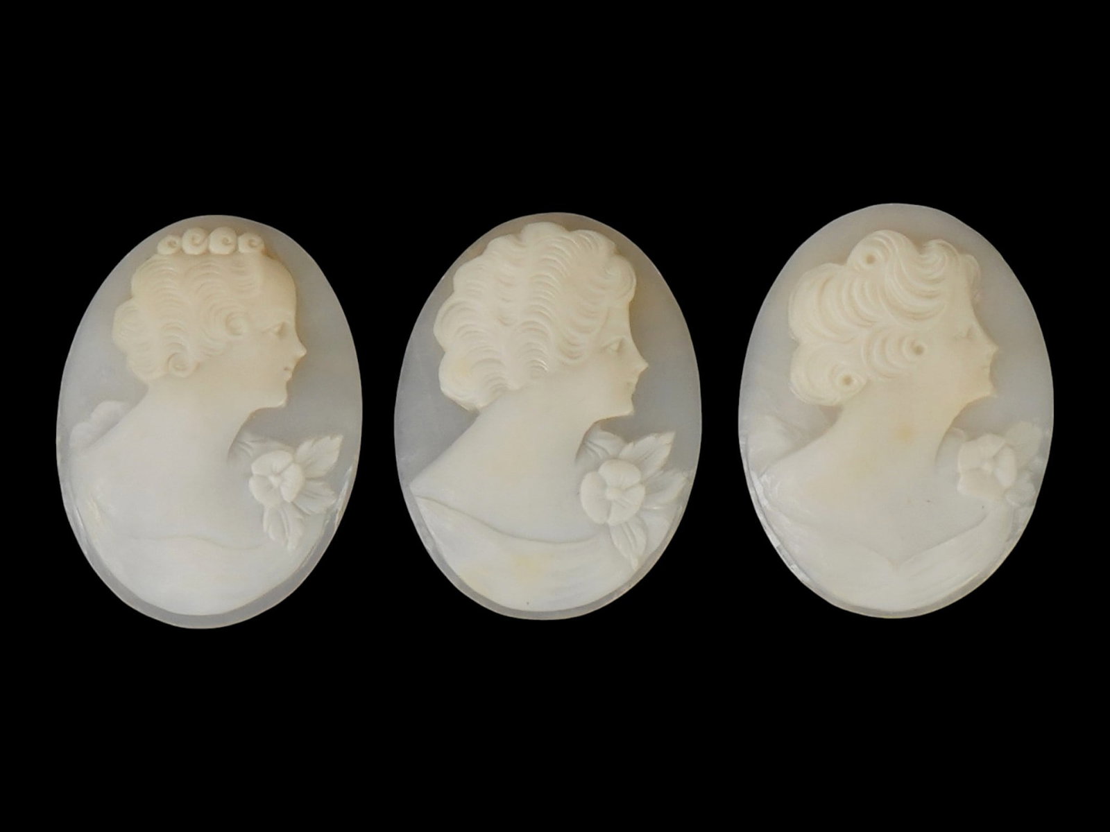 COLLECTION OF CARVED FEMALE PORTRAIT SHELL CAMEOS: A lot of three hand carved white shell cameos. Each piece depicts a female profile portrait rendered in high relief. The pieces are oval in shape, the same size with slight differences in the portrait
