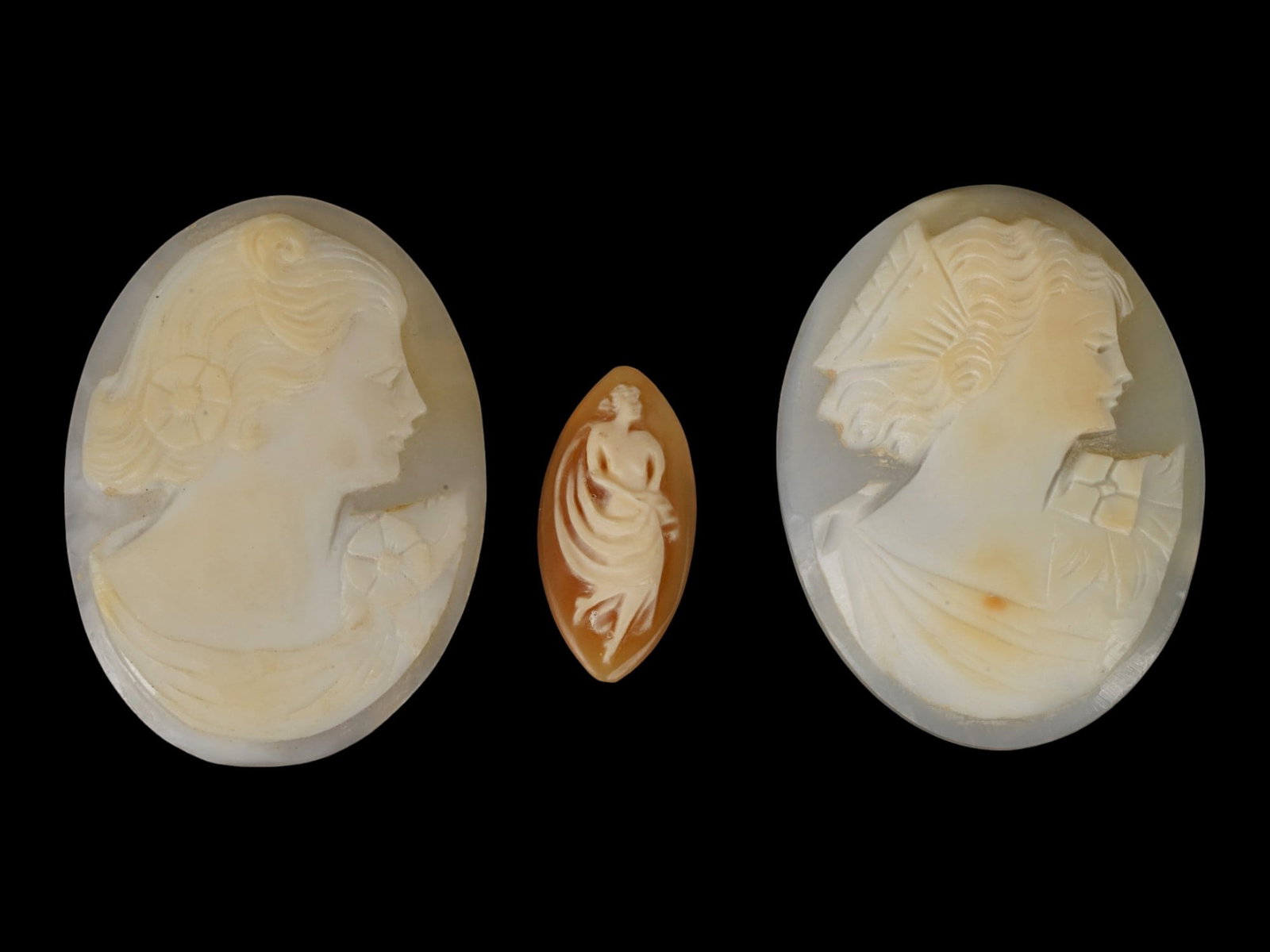 LOT OF CARVED FEMALE PORTRAIT SHELL CAMEO MEDALLIONS: A collection of three hand carved shell cameo medallions. The pieces depict a female profile portrait or a female figure rendered in high relief in the Victorian and Roman manners. One cameo is made i