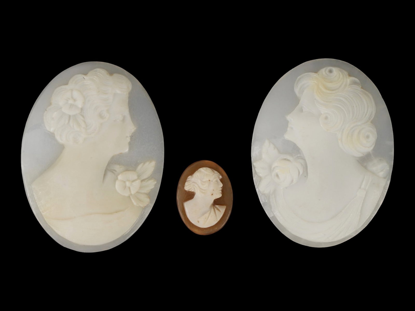 LOT OF CARVED FEMALE PORTRAIT SHELL CAMEO MEDALLIONS: A collection of three hand carved shell cameo medallions. The pieces depict a female profile portrait rendered in high relief in the Victorian and Roman manners. One cameo is made in a smaller size. E