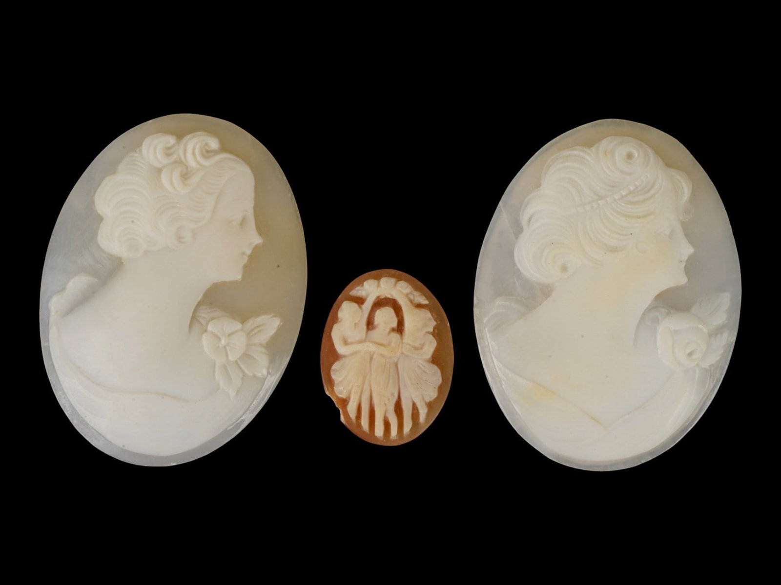 LOT OF CARVED FEMALE PORTRAIT SHELL CAMEO MEDALLIONS: A collection of three hand carved shell cameo medallions. Two pieces depict a female profile portrait rendered in high relief in the Victorian and Roman manners. One cameo represents the Three Graces 
