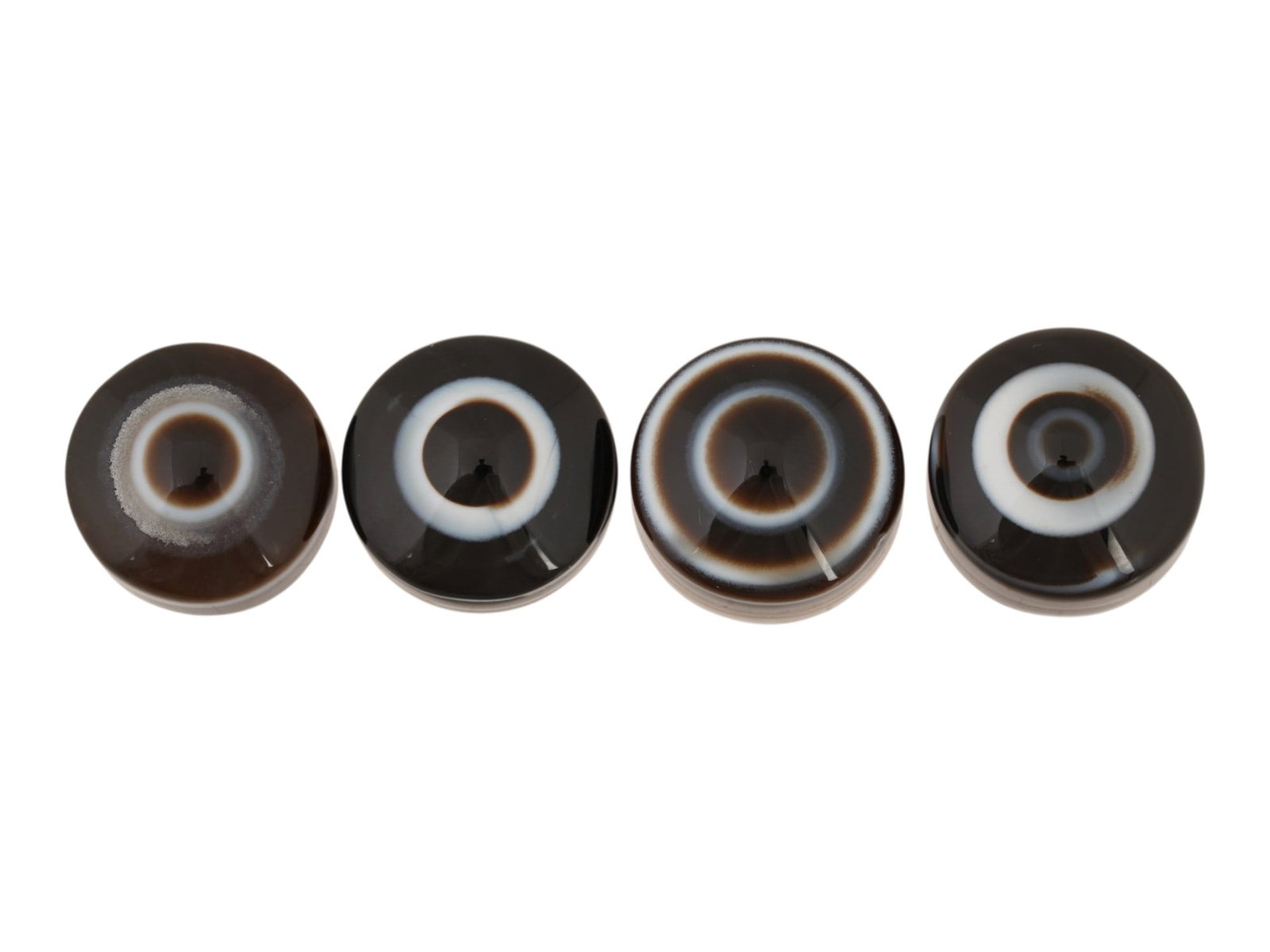 LOT OF NATURAL BULLSEYE BANDED AGATE CABOCHONS: A lot of four natural bullseye banded agate cabochons. The polished gemstones display a concentric eye pattern with alternating brown and white bands. Natural Gemstones And Jewelry Collectibles. THIS