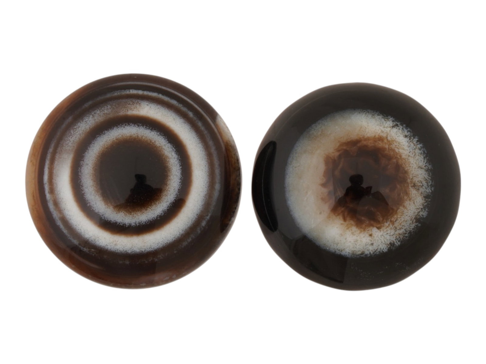 LOT OF TWO NATURAL BULLSEYE BANDED AGATE CABOCHONS: A lot of two large banded agate specimen cabochons. Each is carved into a circular cabochon form, featuring a striking natural bullseye pattern. The pieces have been polished to a high luster on its