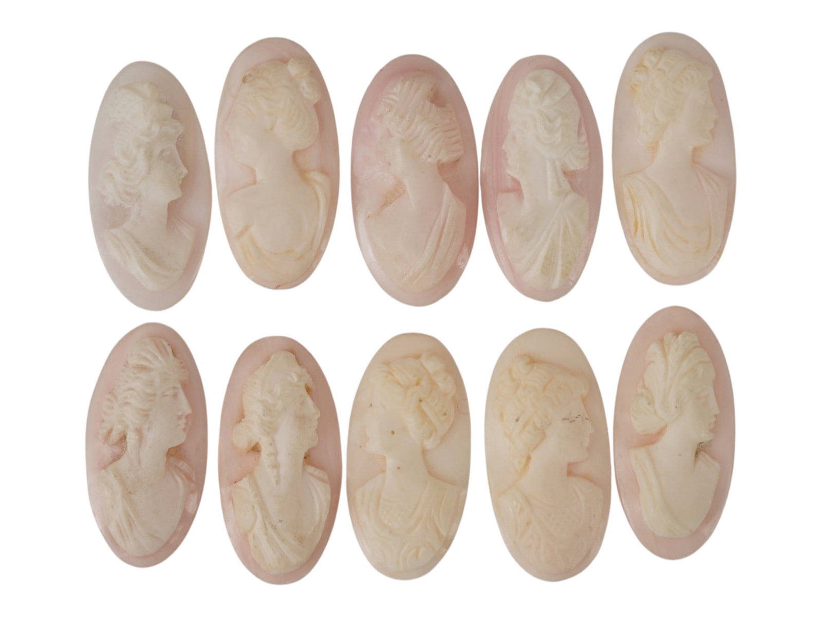 LOT OF FEMALE PORTRAIT CARVED PINK CORAL CAMEOS: A lot of 10 hand carved pink coral cameos. Each piece depicts a female profile portrait rendered in high relief. Elongated oval shape. Collectible Jewelry And Glyptic Art, Sculpture. THIS LOT IS ELIGI