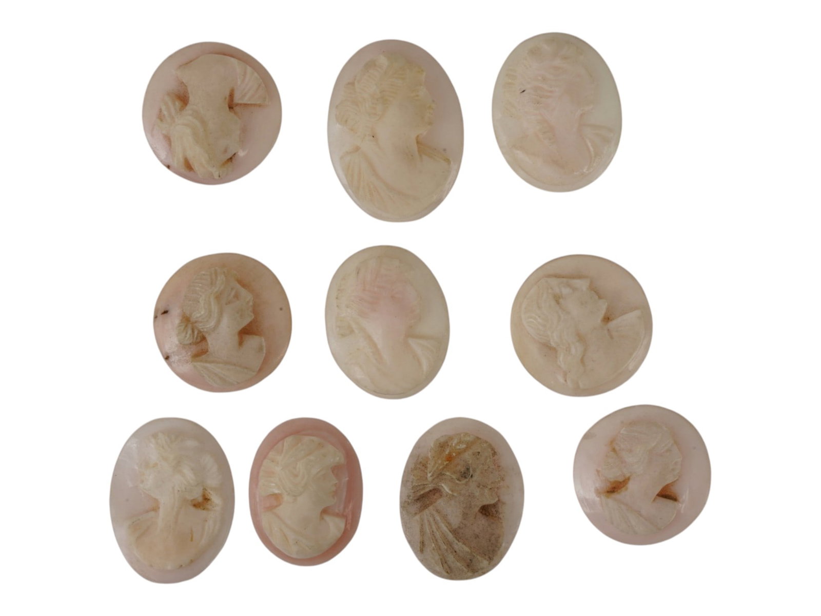 LOT OF FEMALE PORTRAIT CARVED PINK CORAL CAMEOS: A lot of 10 hand carved pink coral cameos. Each piece depicts a female profile portrait rendered in high relief. Round and oval shape. Collectible Jewelry And Glyptic Art, Sculpture. THIS LOT IS ELIGI