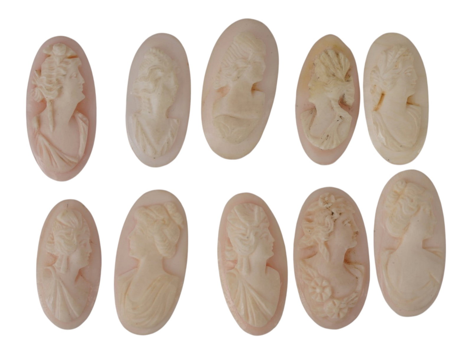 LOT OF FEMALE PORTRAIT CARVED PINK CORAL CAMEOS: A lot of 10 hand carved pink coral cameos. Each piece depicts a female profile portrait rendered in high relief. Elongated oval shape. Collectible Jewelry And Glyptic Art, Sculpture. THIS LOT IS ELIGI