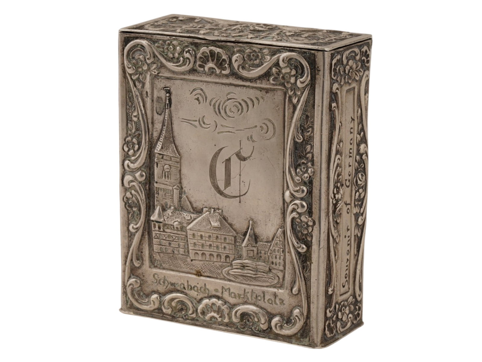 GERMAN SCHWABACH STERLING SILVER CIGARETTE CASE: A German sterling silver cigarette case with a hinged lid. The front depicts a relief image of Marktplatz square in the city of Schwabach. The box is richly decorated with floral and scroll relief pat