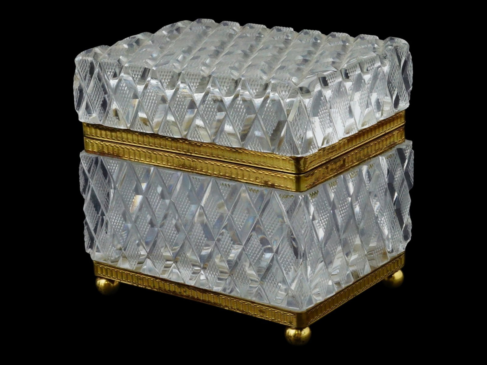 ANTIQUE FRENCH LIDDED CUT CRYSTAL JEWELRY CASKET: An antique French cut crystal jewelry casket. The lid and base feature a deep diamond-point cut with frosted cross-hatch centers for brilliant refraction, joined by chased gilt bronze mounts with a fo
