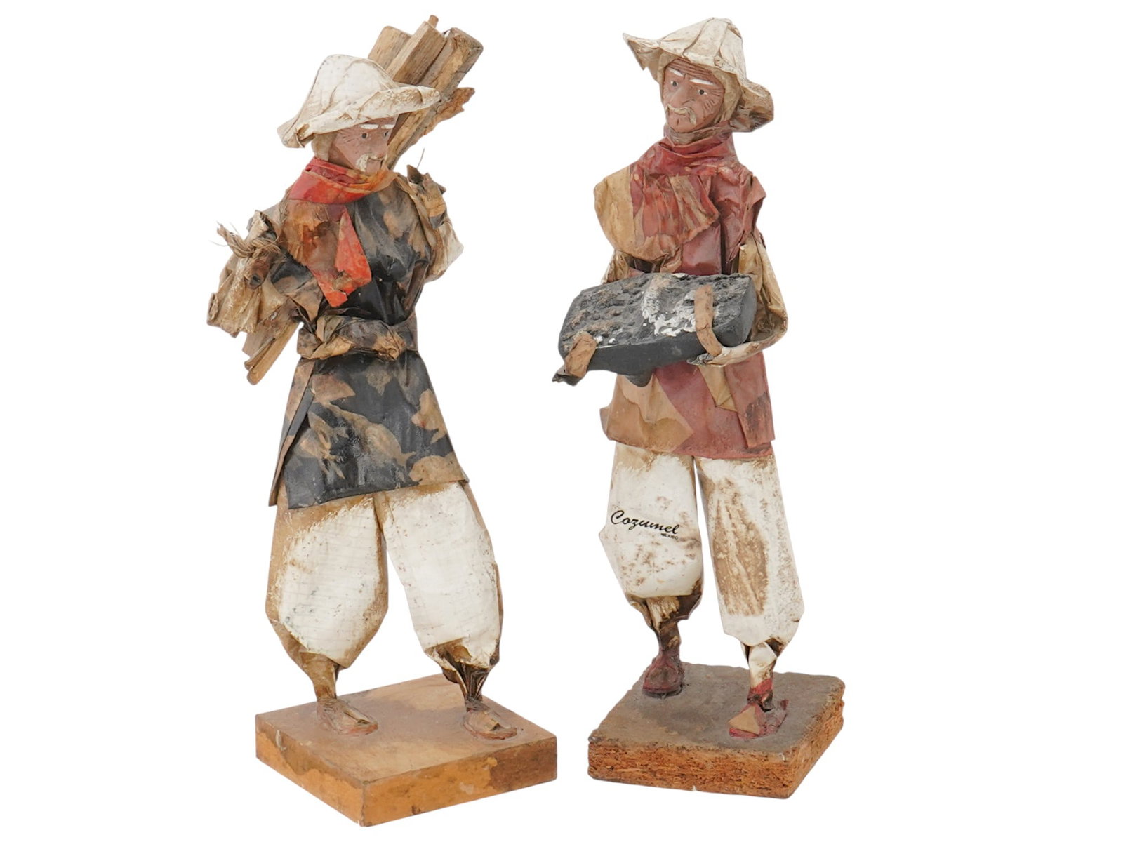 TWO MEXICAN PAPER MACHE FOLK ART SCULPTURES: A lot of two Mexiacan sculptures made of colored paper and other materials. The figures depict laborers. One figure carries a bundle of wood on his shoulder. The other figure holds a heavy, rectangula