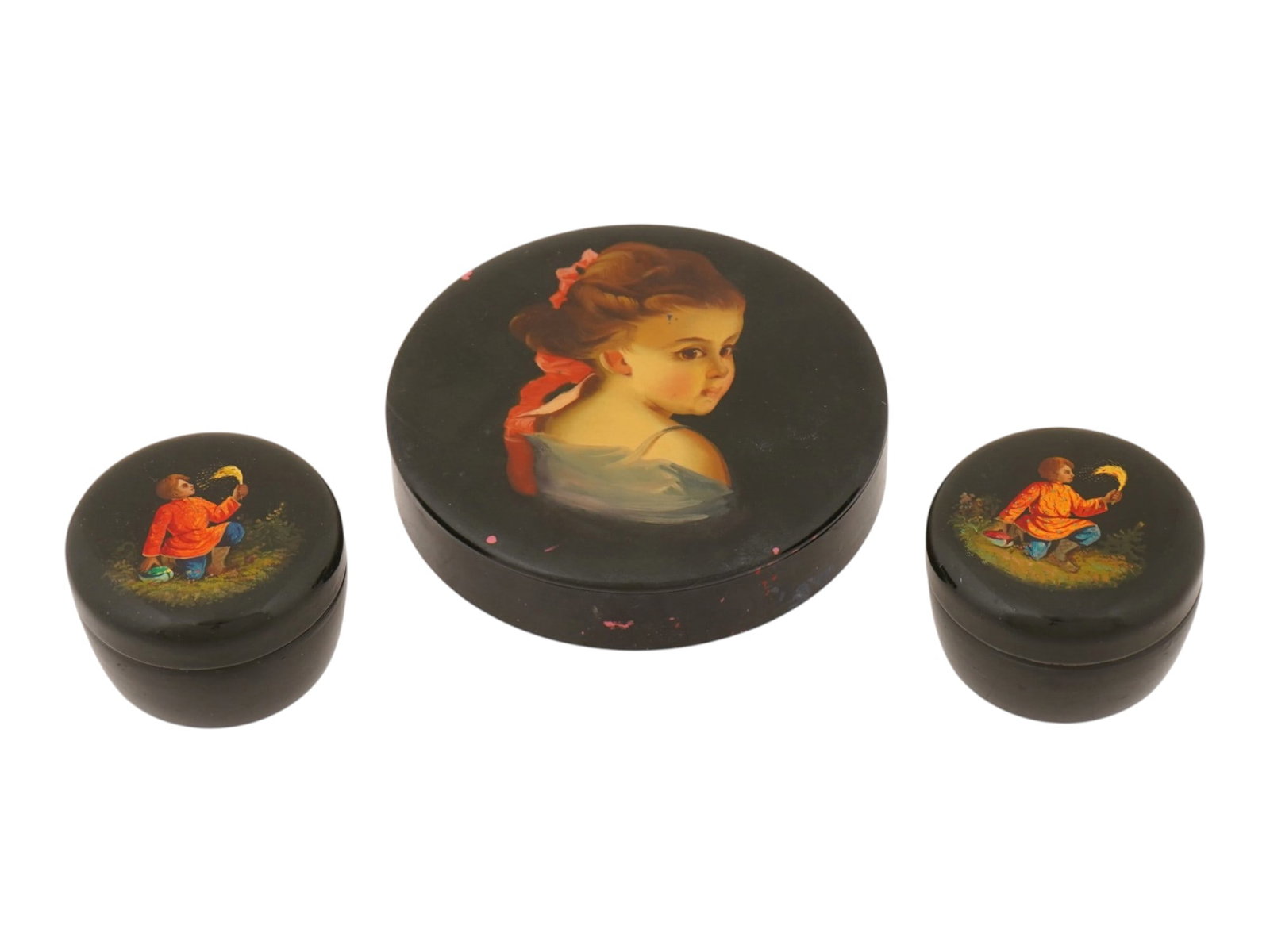 LOT OF THREE LACQUER HAND PAINTED WOODEN BOXES: A collection of three circular boxes crafted from turned wood with a polished black lacquer finish. The largest lid is adorned with a hand painted portrait of a young woman in profile, while the two