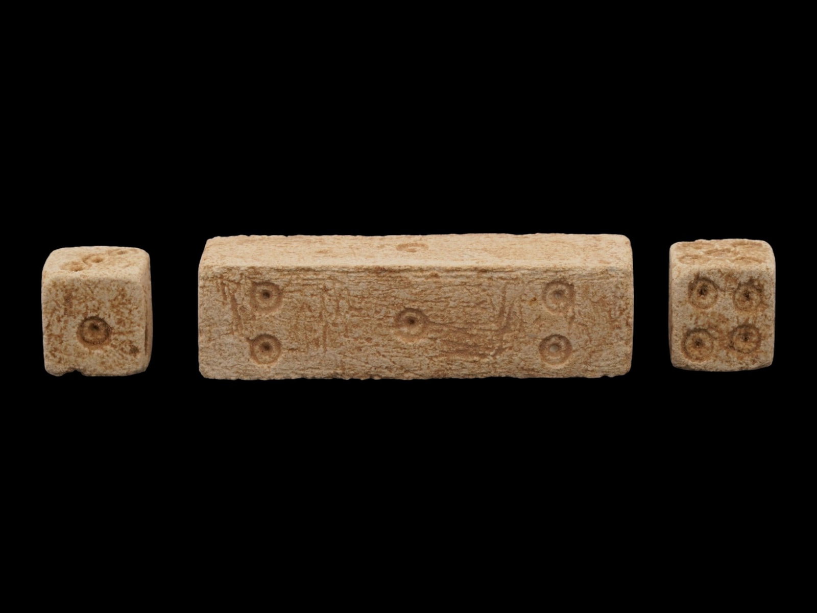 LOT OF ANCIENT ROMAN EMPIRE STONE DICE: A lot of three Ancient Roman stone dice. Imperial Rome era, 100 to 300 AD. Two small cubic gaming objects and a single large elogated dice. Dice were widely used across the Roman Empire for board game