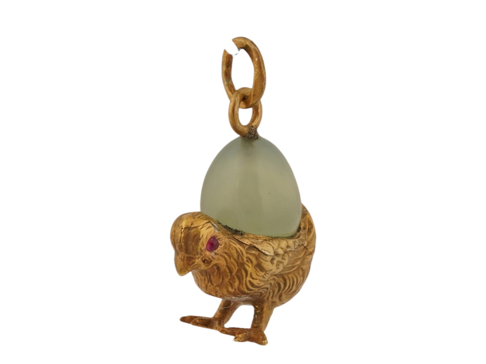 RUSSIAN SILVER BOWENITE CHICK EASTER EGG PENDANT W RUBY: A Russian gilt silver pendant modeled as a chick with eyes set with ruby cabochons holding a carved Bowenite egg. Finely detailed with carved patterns. Hallmarked with the 88 Russian silver standard