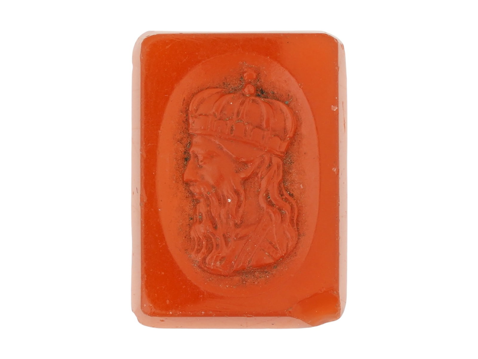 ANTIQUE CARVED CARNELIAN INTAGLIO WITH CROWNED MALE: An antique intaglio, carved from a red stone most likely carnelian, featuring a recessed profile bust of a bearded, crowned male figure facing left, executed in a style evocative of ancient glyptic ar