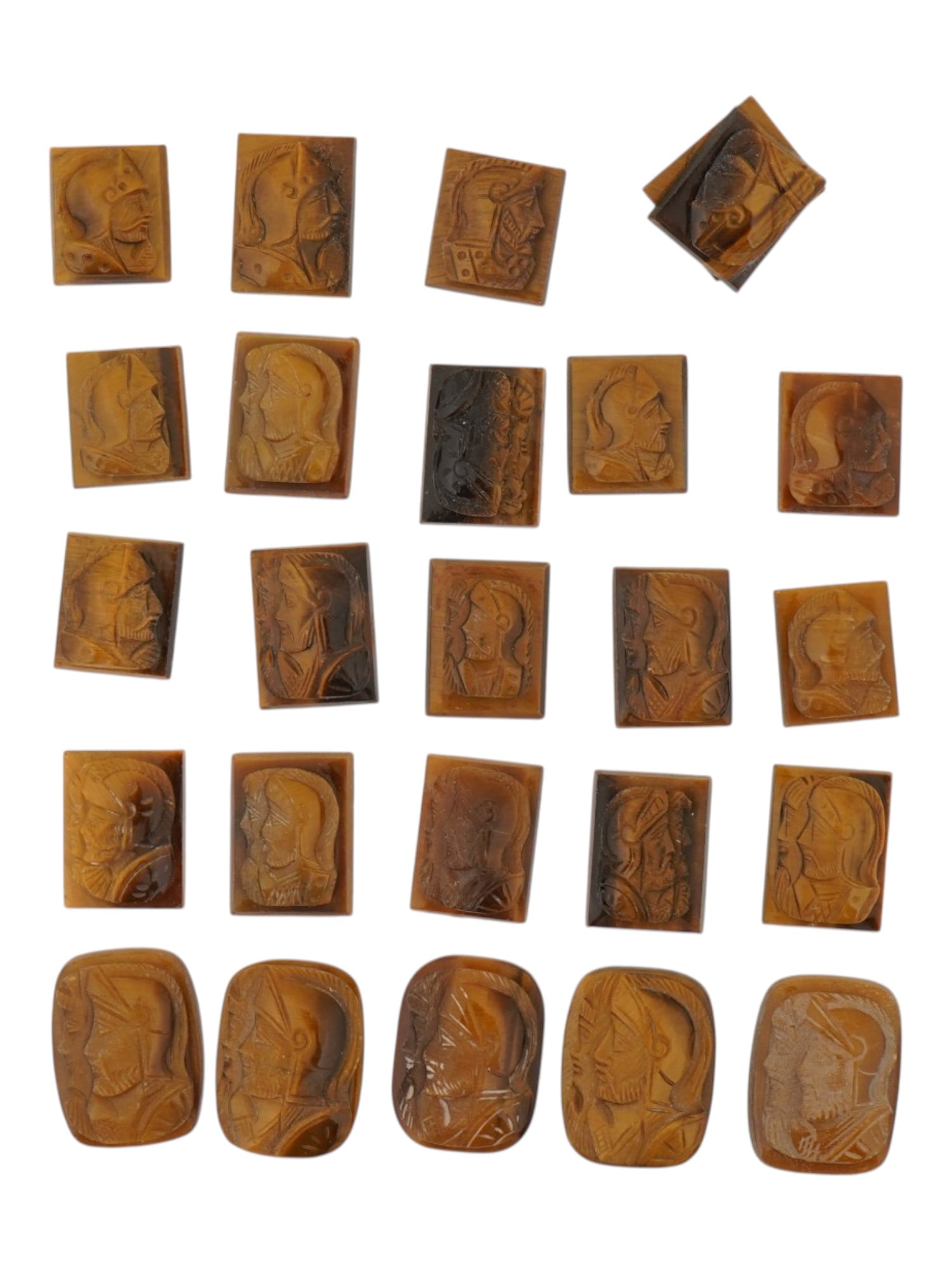 COLLECTION OF PORTRAIT HAND CARVED TIGERS EYE CAMEOS: A collection of twenty four hand carved tigers eye cameo medallions. The lot includes rectangular carvings depicting single and double profile armored warriors in the Roman manner. Made for rings, cuf