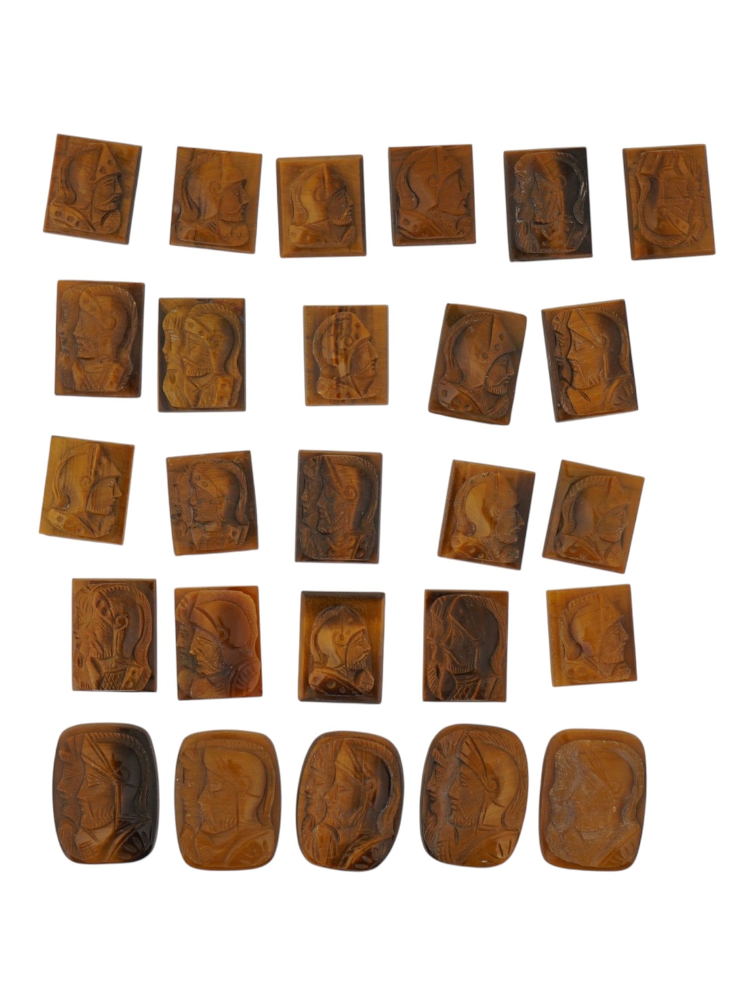 COLLECTION OF PORTRAIT HAND CARVED TIGERS EYE CAMEOS: A collection of twenty six hand carved tigers eye cameo medallions. The lot includes rectangular carvings depicting single and double profile armored warriors in the Roman manner. Made for rings, cuff