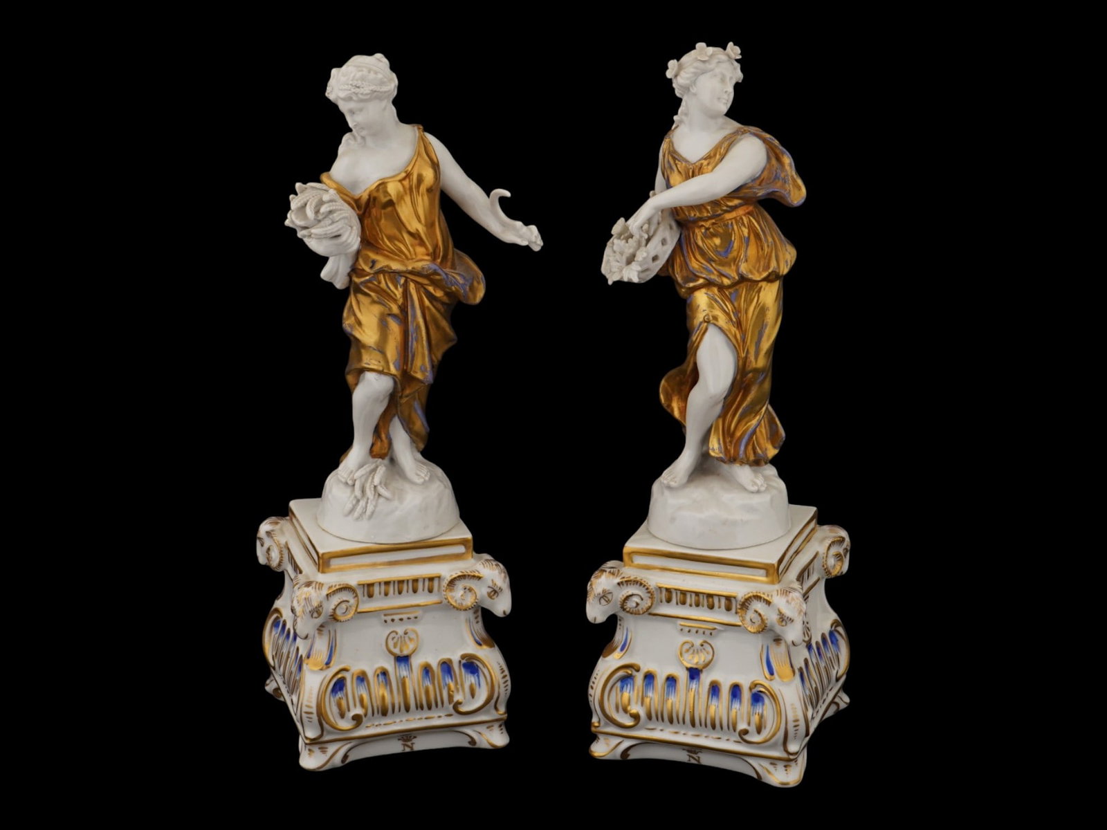 PAIR OF ITALIAN CAPODIMONTE PORCELAIN FIGURINES: A pair of Capodimonte porcelain figurines depicting two neoclassical female subjects, likely allegorical muses, standing upon ornate pedestal bases. Each figure is rendered in white glaze with elabora