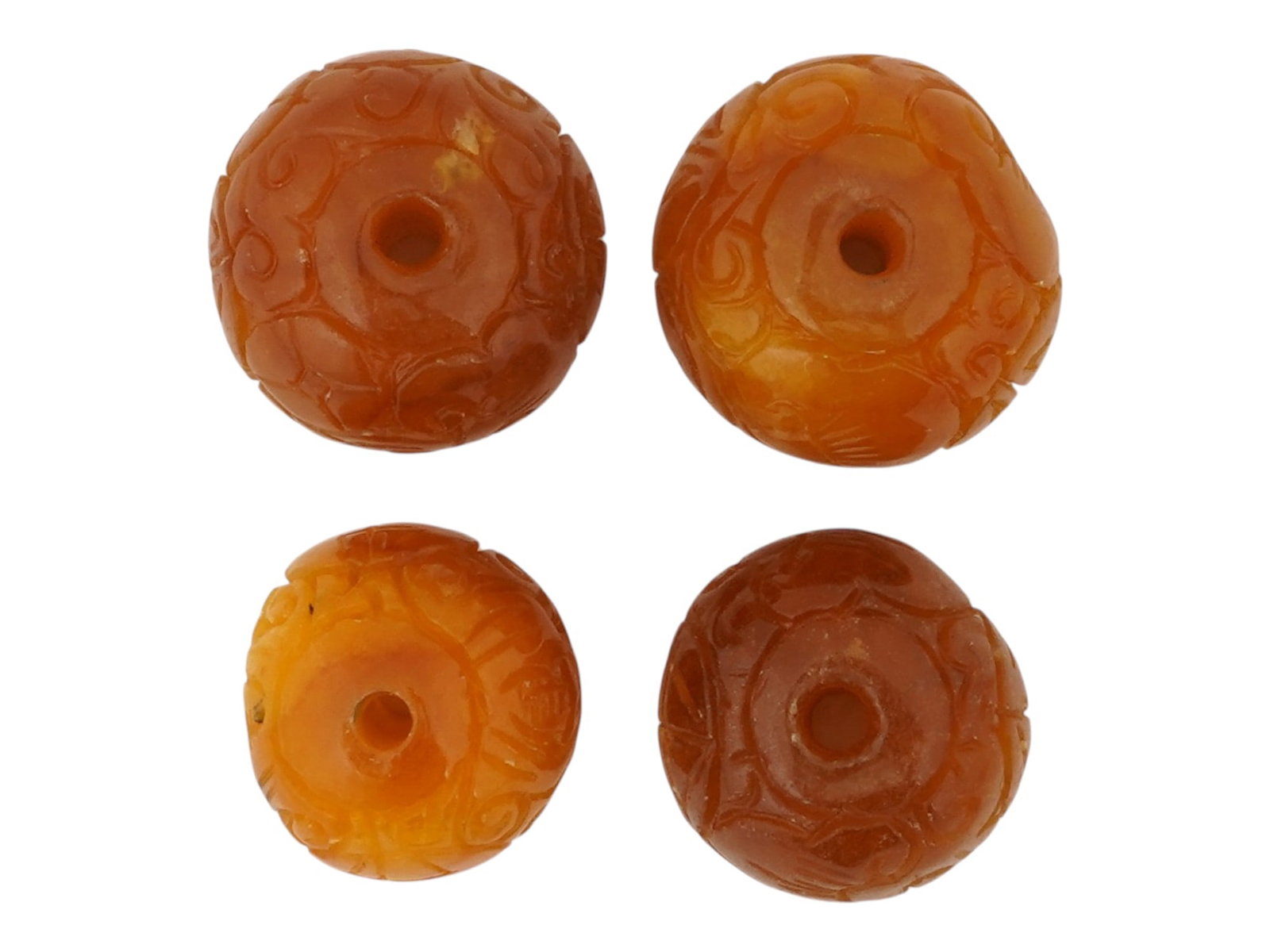 COLLECTION OF FOUR CHINESE HAND CARVED JADE BEADS: A collection of four hand carved jade beads characterized by a deep russet and golden brown tonality with natural variegated mottling throughout. Each element is fashioned into a rounded form with a c