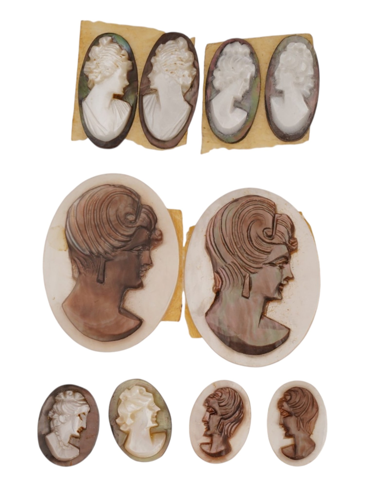 COLLECTION OF TEN VINTAGE HAND CARVED SHELL CAMEOS: A collection of ten vintage hand-carved shell cameos depicting classical and mid-century female profile portraits. Carved from mother-of-pearl, abalone, and black-lipped pearl oyster shell, the cameos