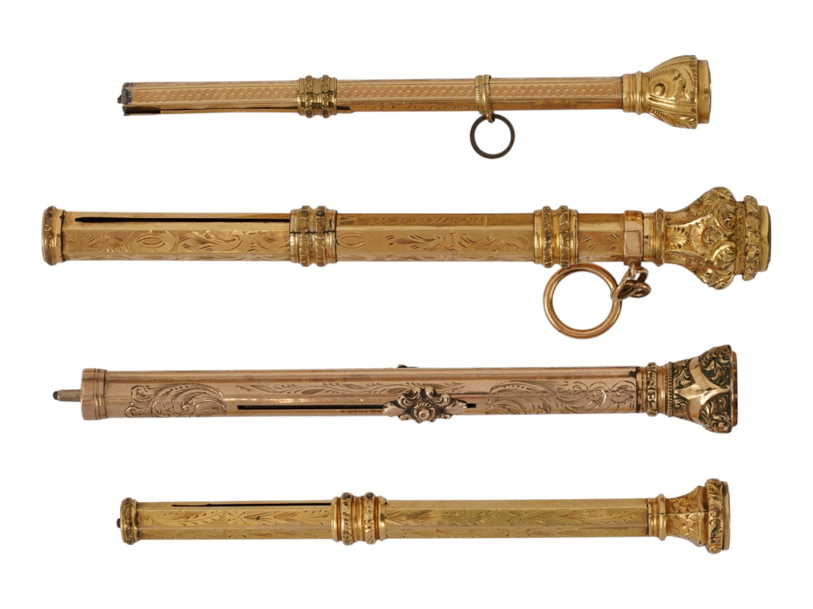 ANTIQUE VICTORIAN GOLD PLATED PENCIL AND PENS 1890: A lot of four antique Victorian-era gold-plated writing instruments, a retractable pencil, and pen holders, 1890. They feature column-shaped engraved designs on the body and decorative finials topped 