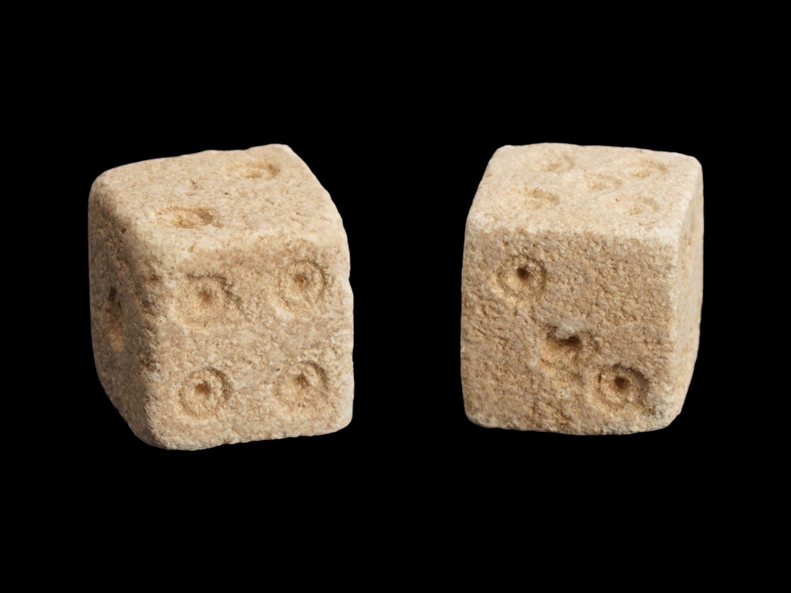 PAIR OF ANCIENT ROMAN STONE DICE 100 TO 300 AD: A pair of ancient Roman hand carved stone dice, ca. 100 to 300 AD. Crafted with precision and care, these artifacts offer a tangible connection to the everyday life and leisure activities of the past.