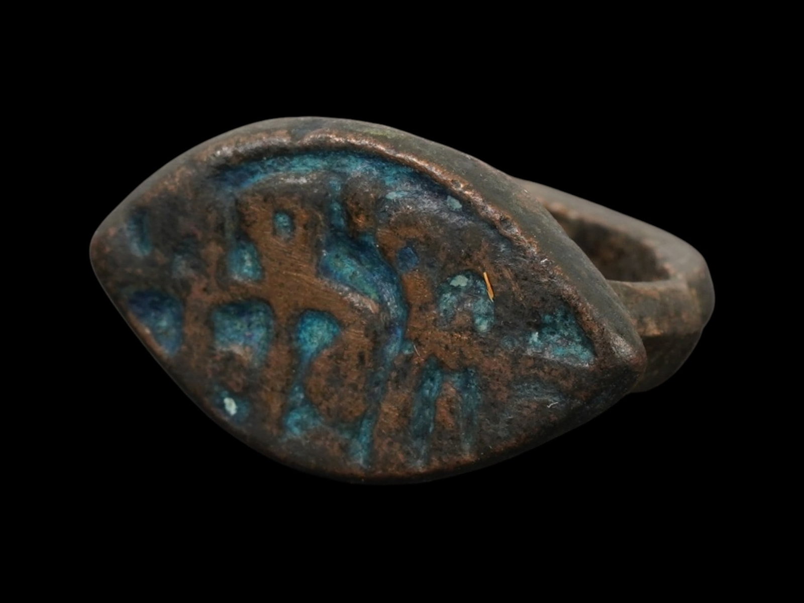 ANCIENT ISLAMIC BRONZE RING WITH ENGRAVED INSCRIPTION: An ancient Islamic bronze ring, dating from approximately 600 to 800 AD, featuring an engraved inscription on the bezel. The ring displays the simple, robust form characteristic of early Islamic bronz