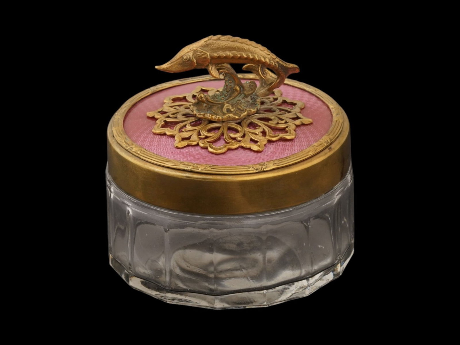 RUSSIAN GLASS SILVER AND ENAMEL CAVIAR JAR SERVER: A Russian glass, silver and enamel caviar jar server. The glass body is complemented by a git silver lid. The lids surface is pink guilloche enameled. Adorned with a figure of a sturgeon, surrounded b