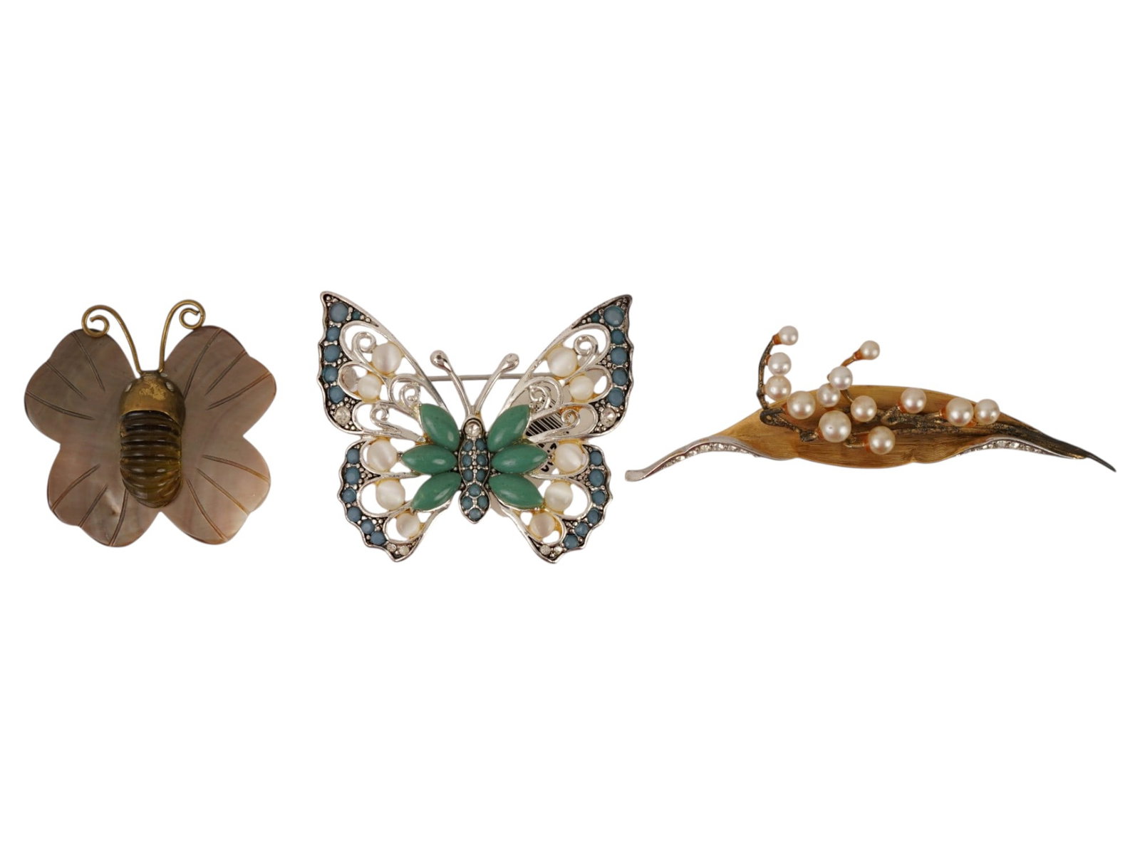 COLLECTION OF FIGURAL COSTUME JEWELRY BROOCHES: A collection of three costume jewelry brooches, including a gilt butterfly, a silver tone butterfly with green rhinestones and pearls, and a textured foliage design brooch graduated pearls. Marked, Fa