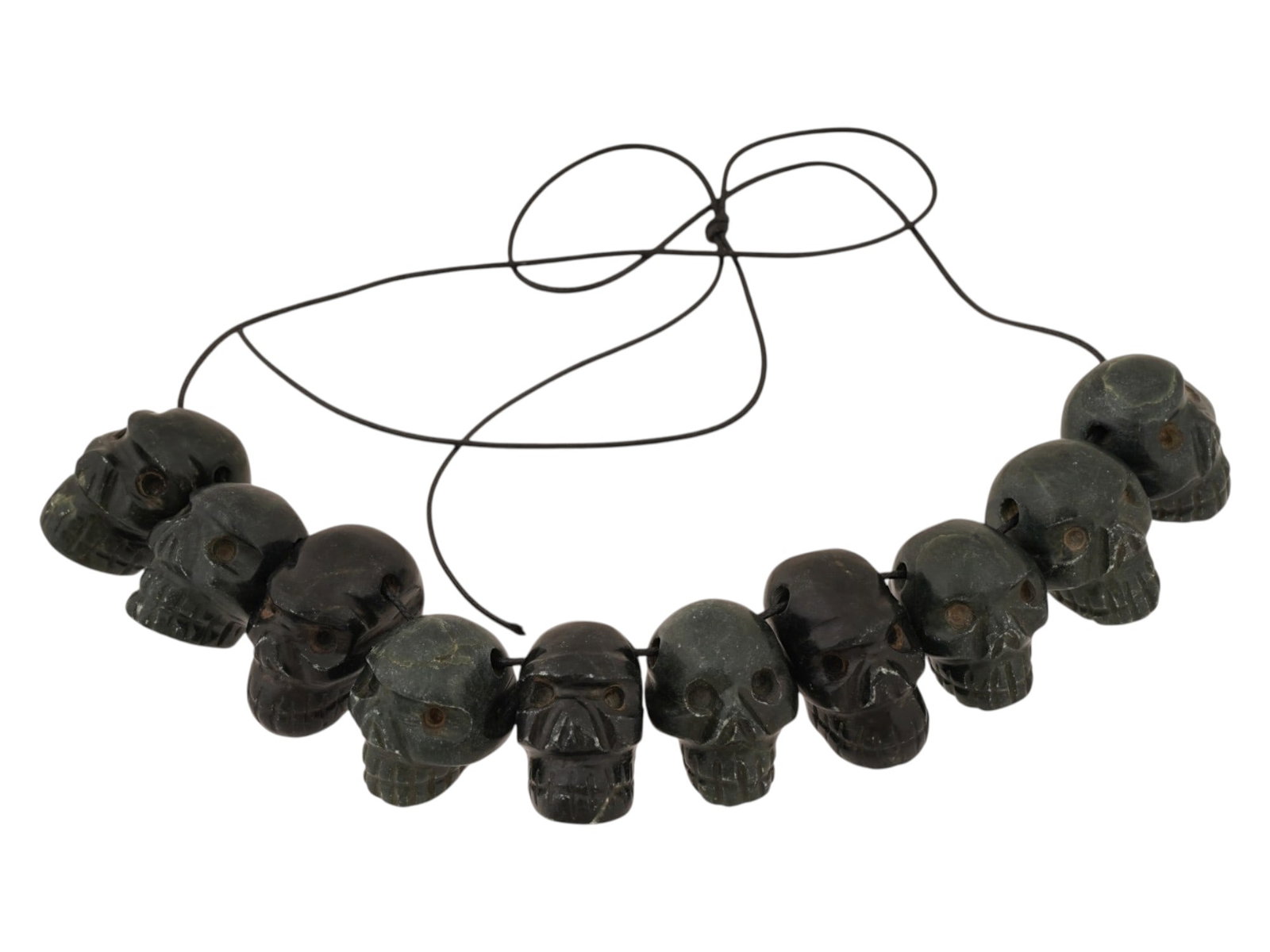 LOT OF HAND CARVED JADE FIGURAL BEADS FROM GUATEMALA: A lot of ten hand carved beads fashioned from black jadeite jade originating from Guatemala. Each individual component is sculpted into the form of a skull. The beads are presented on a temporary stri