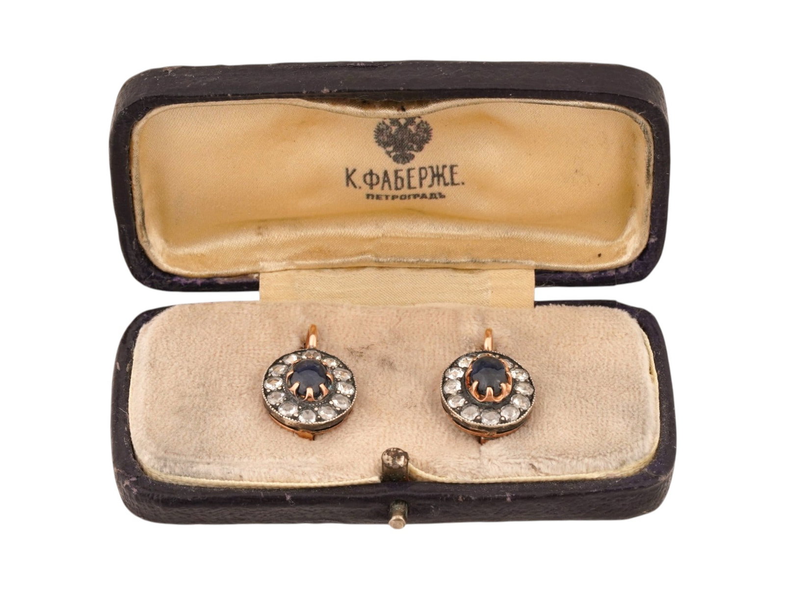 RUSSIAN 14K GOLD EARRINGS W SAPPHIRES AND DIAMONDS: A pair of Russian cluster earrings crafted in 14K rose Gold. Each features a centrally set oval cut blue sapphire framed by a halo of round cut diamonds. The settings are designed with a classic scall