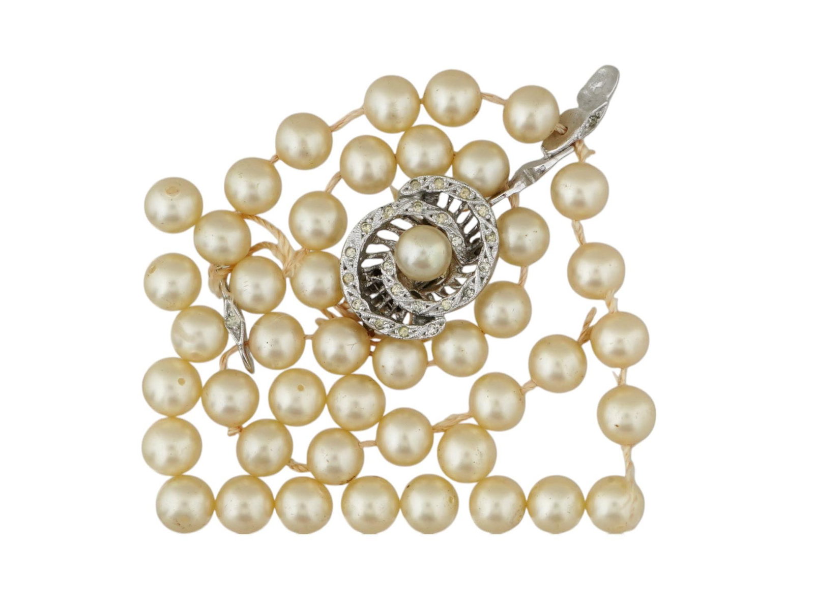 VINTAGE PEARL BEADED NECKLACE WITH ORNATE CLASP: A vintage beaded necklace made of rounded pearl beads with a clasp. The pearls are off white with a subtle sheen. The clasp has a circular, design encrusted with small stones. Vintage and Modern Natur