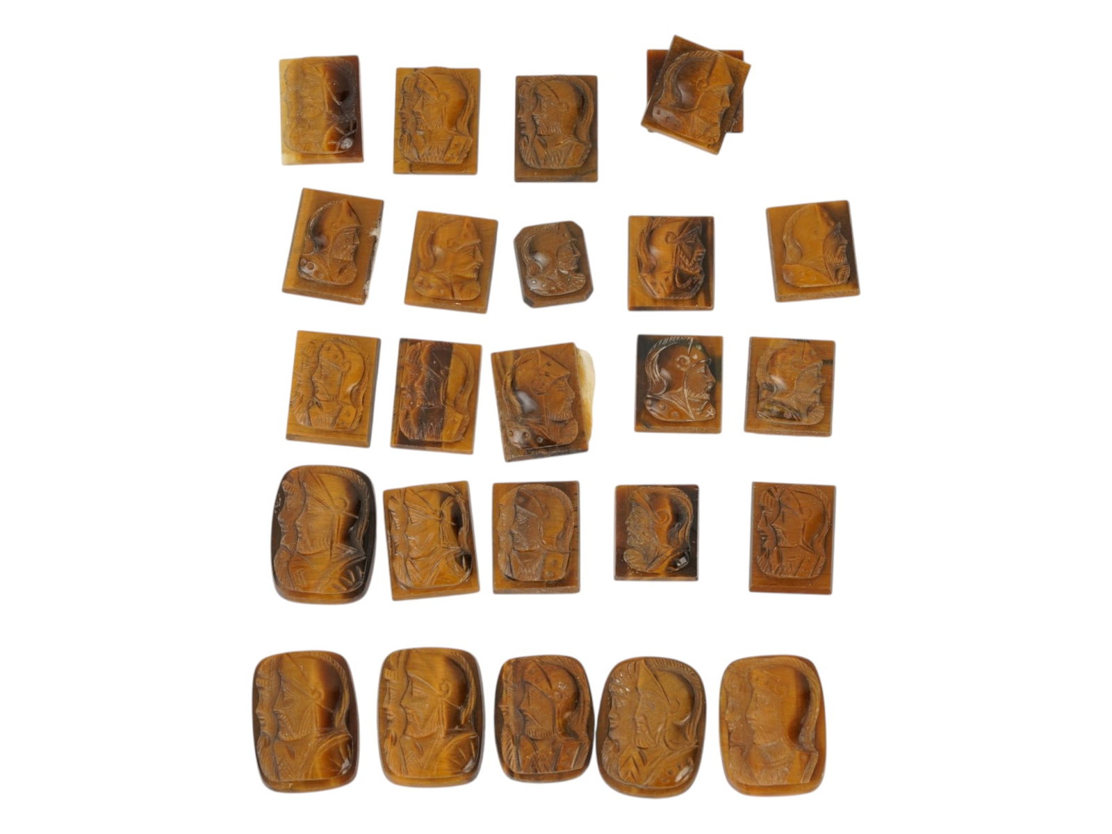 COLLECTION OF PORTRAIT HAND CARVED TIGERS EYE CAMEOS: A collection of twenty four hand carved tigers eye cameo medallions. The lot includes rectangular carvings depicting single and double profile armored warriors in the Roman manner. Made for rings, cuf