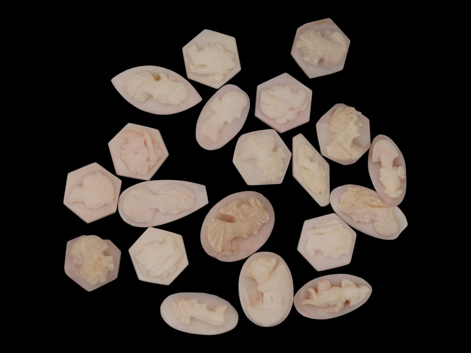 LOT OF FEMALE PORTRAIT CARVED PINK CORAL CAMEOS: A lot of 20 hand carved pink coral cameos. Each piece depicts a female profile portrait rendered in high relief. Oval, hexagon, marquise shape. Collectible Jewelry And Glyptic Art, Sculpture. THIS LOT