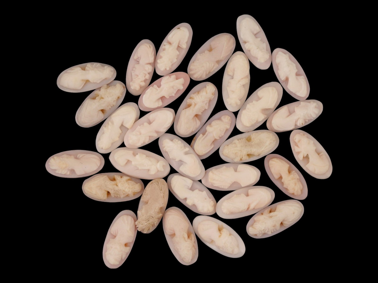LOT OF FEMALE PORTRAIT CARVED PINK CORAL CAMEOS: A lot of 30 hand carved pink coral cameos. Each piece depicts a female profile portrait rendered in high relief. Elongated oval shape. Collectible Jewelry And Glyptic Art, Sculpture. THIS LOT IS ELIGI